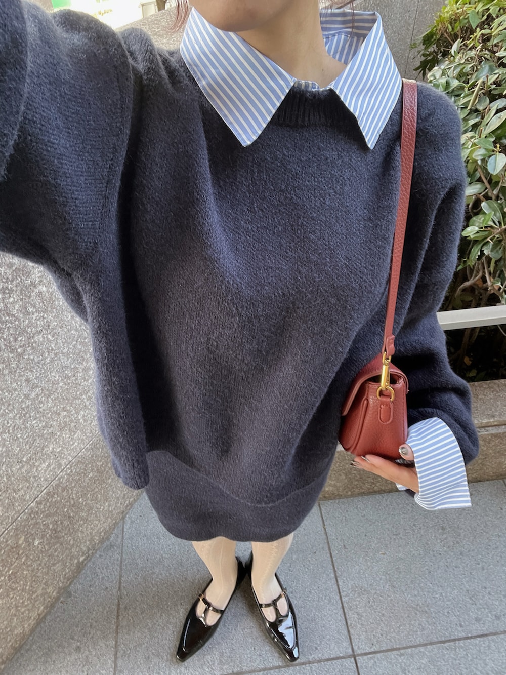 ブルー系のニット/セーター、ブルー系のスカート、レッド系のショルダーバッグを着用したレディースの秋コーディネートの3枚目の写真