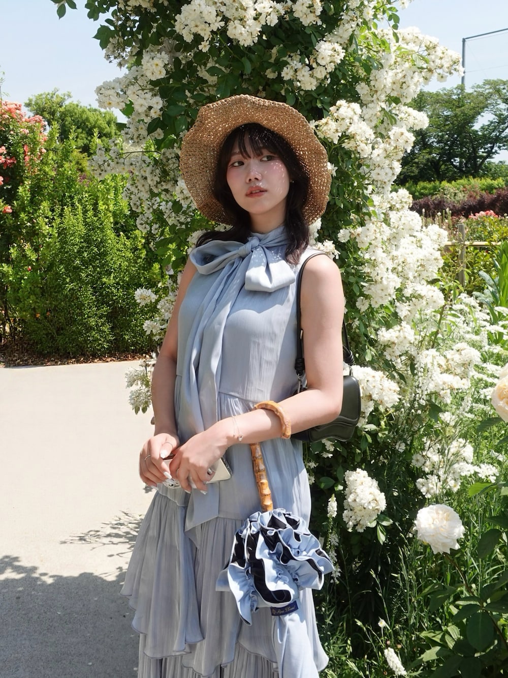 ブルー系のワンピース、ブラック系のショルダーバッグ、シルバー系のサンダルを着用したレディースの夏コーディネートの2枚目の写真