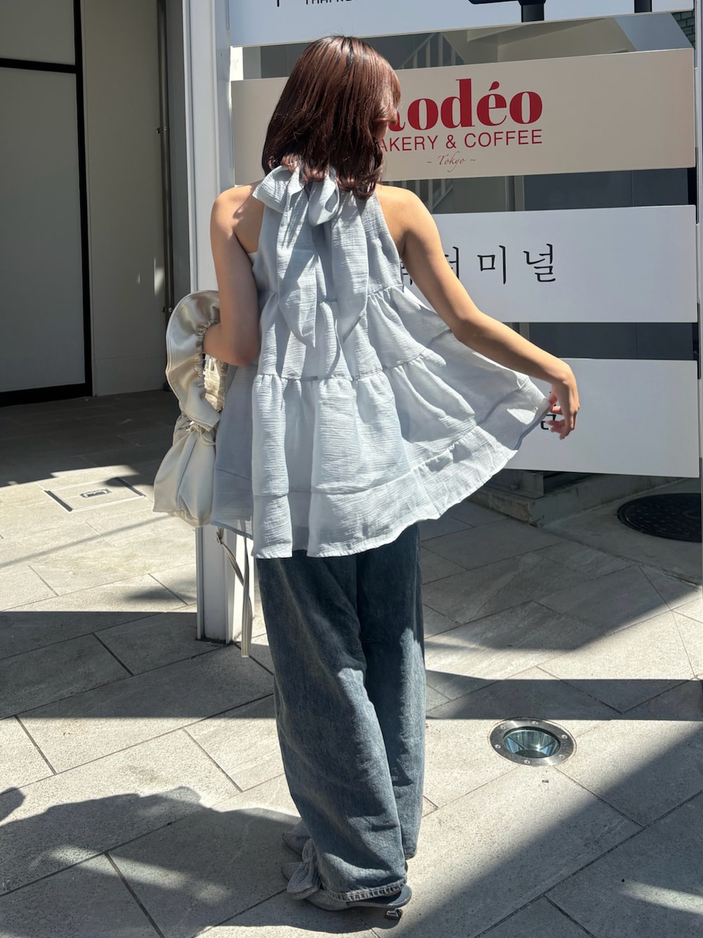 シルバー系のパンプス、ブルー系のシャツ/ブラウス、ブルー系のデニムパンツを着用したレディースの夏コーディネートの2枚目の写真