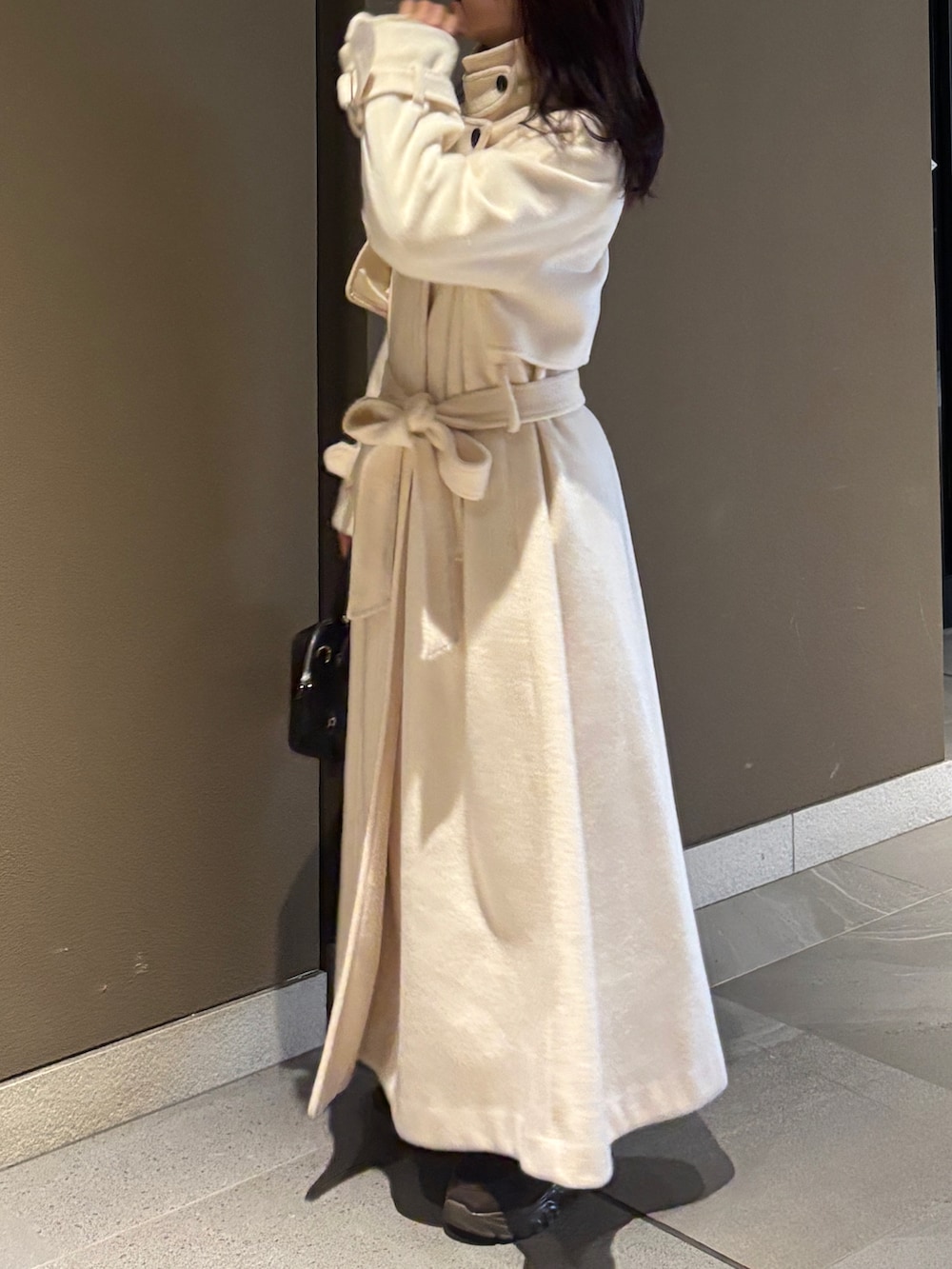 ホワイト系のステンカラーコート、ブラック系のボストンバッグ、ブラウン系のローファーを着用したレディースの冬コーディネートの3枚目の写真