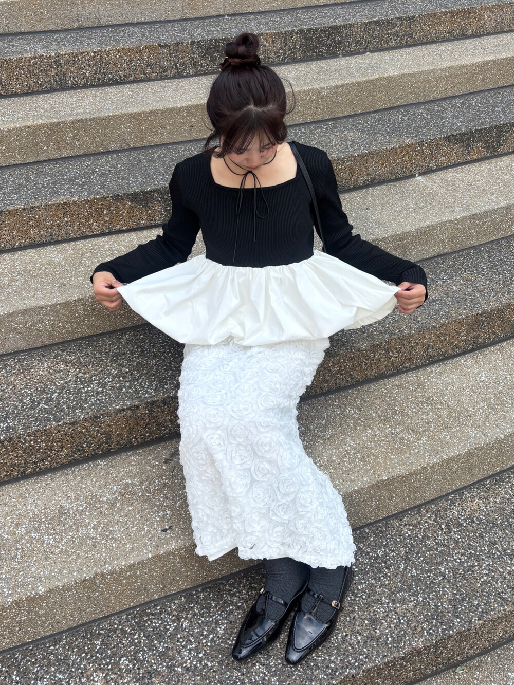 ブラック系のニット/セーター、ホワイト系のスカート、ブラック系のショルダーバッグを着用したレディースの秋コーディネートの3枚目の写真