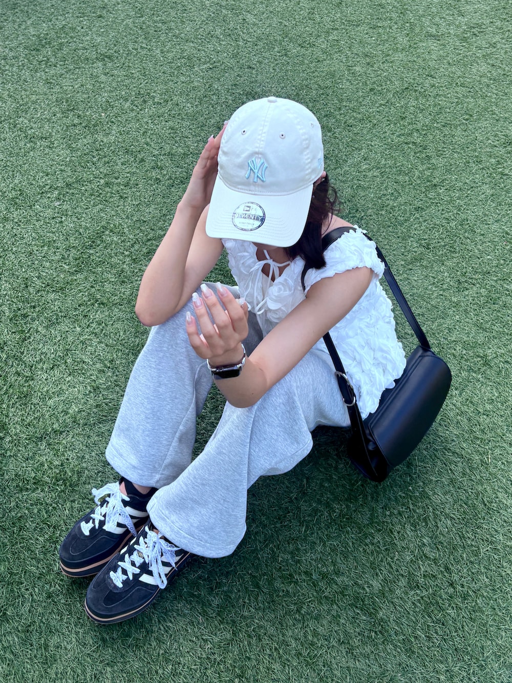 グレー系のスウェットパンツ、ブラック系のショルダーバッグ、ブラック系のスニーカーを着用したレディースの夏コーディネートの2枚目の写真