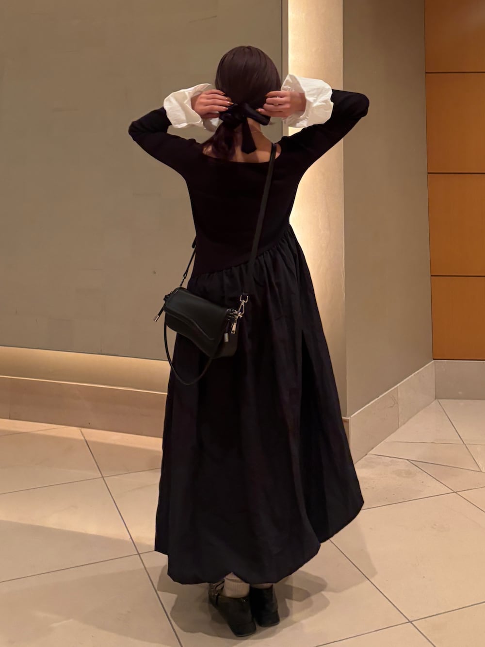 ブラック系のワンピース、ブラック系のショルダーバッグ、ブラック系のパンプスを着用したレディースの冬コーディネートの2枚目の写真