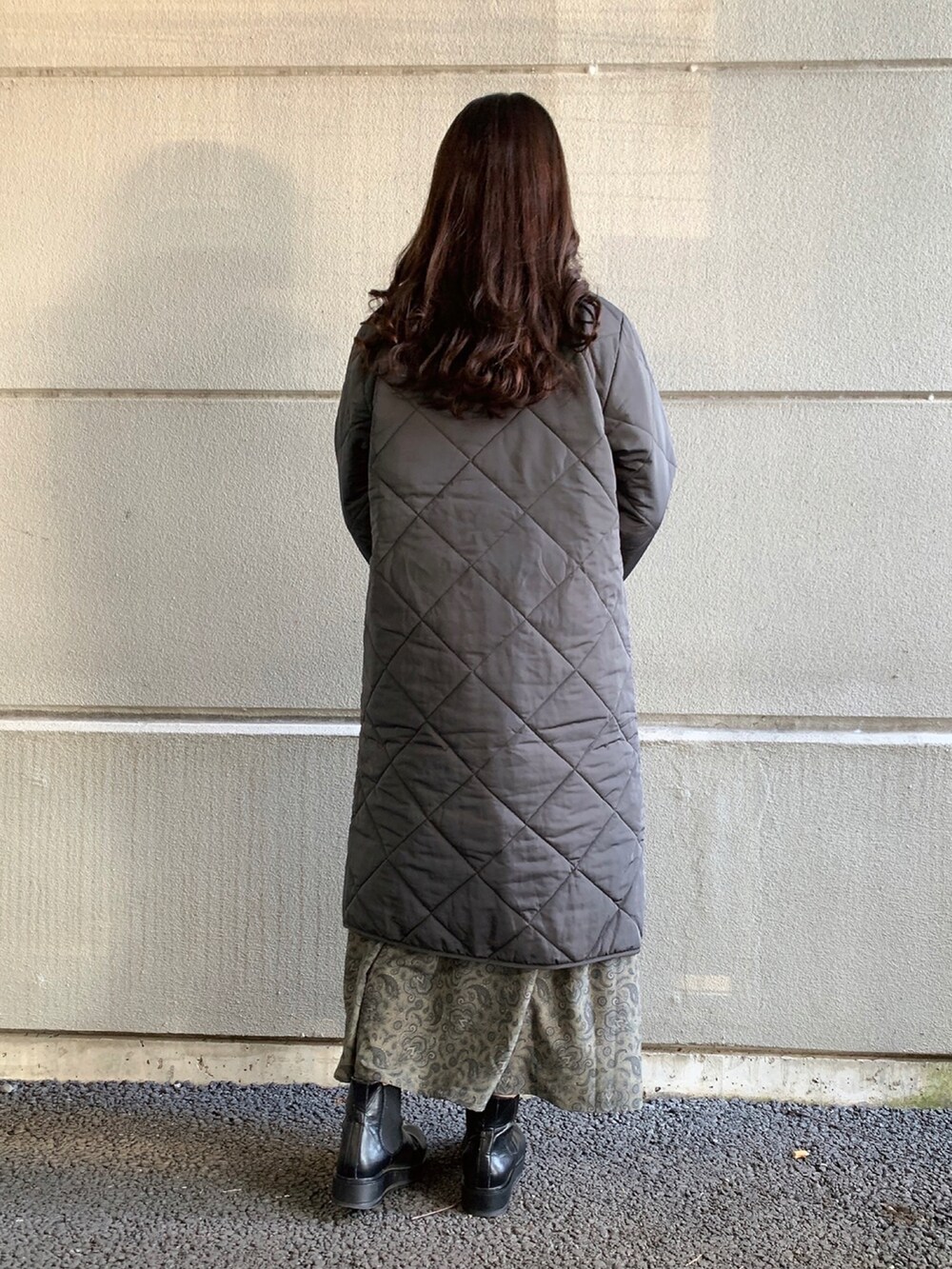 グリーン系のワンピース、ブラック系のその他アウター、ベージュ系のニット/セーターを着用したレディースの冬コーディネートの2枚目の写真