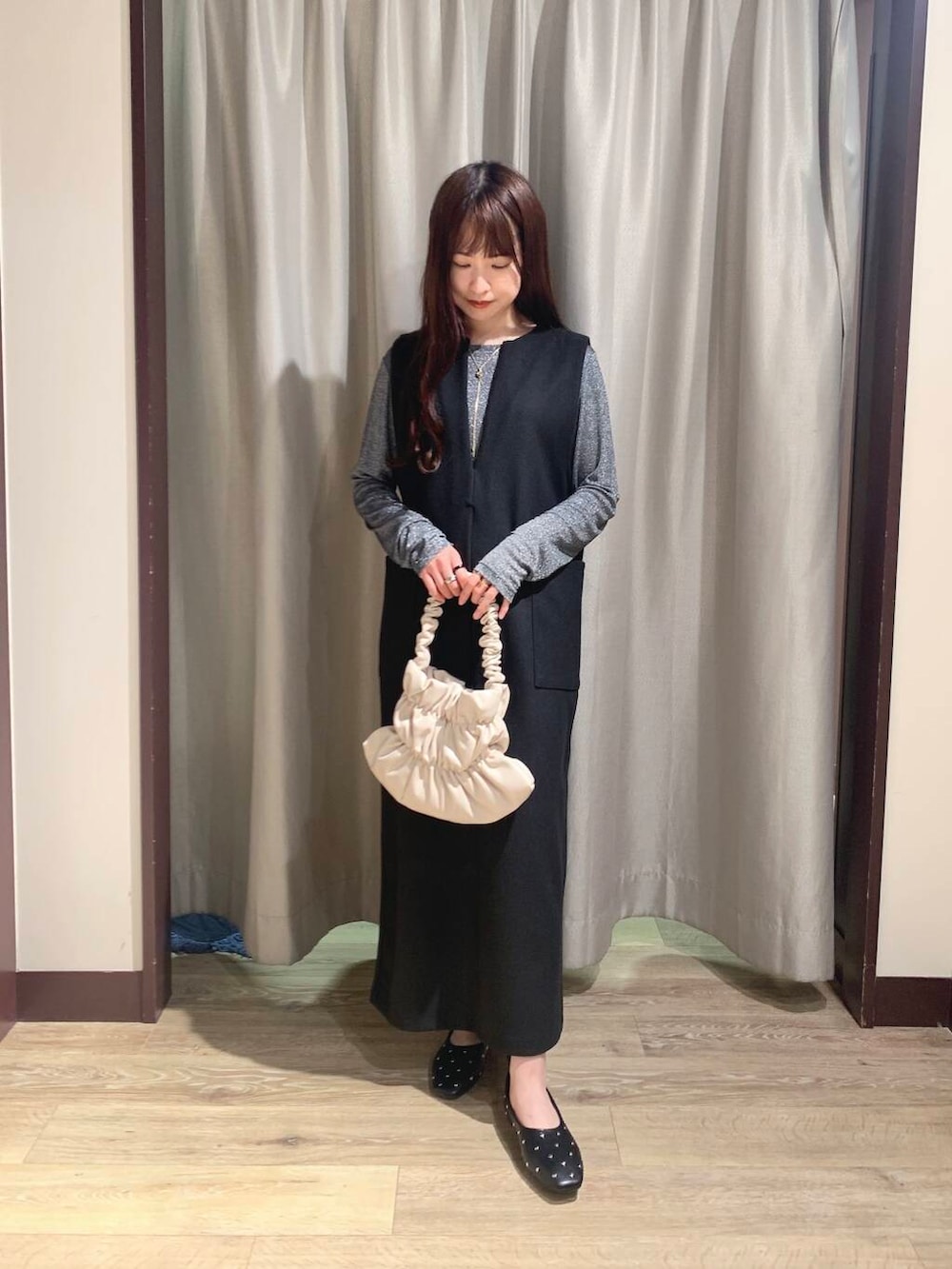 ホワイト系のハンドバッグ、ブラック系のパンプス、ブラック系のジャンパースカートを着用したレディースの秋コーディネートの2枚目の写真