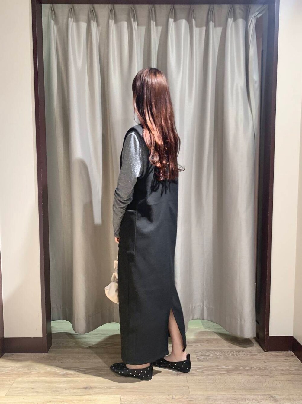 ホワイト系のハンドバッグ、ブラック系のパンプス、ブラック系のジャンパースカートを着用したレディースの秋コーディネートの3枚目の写真