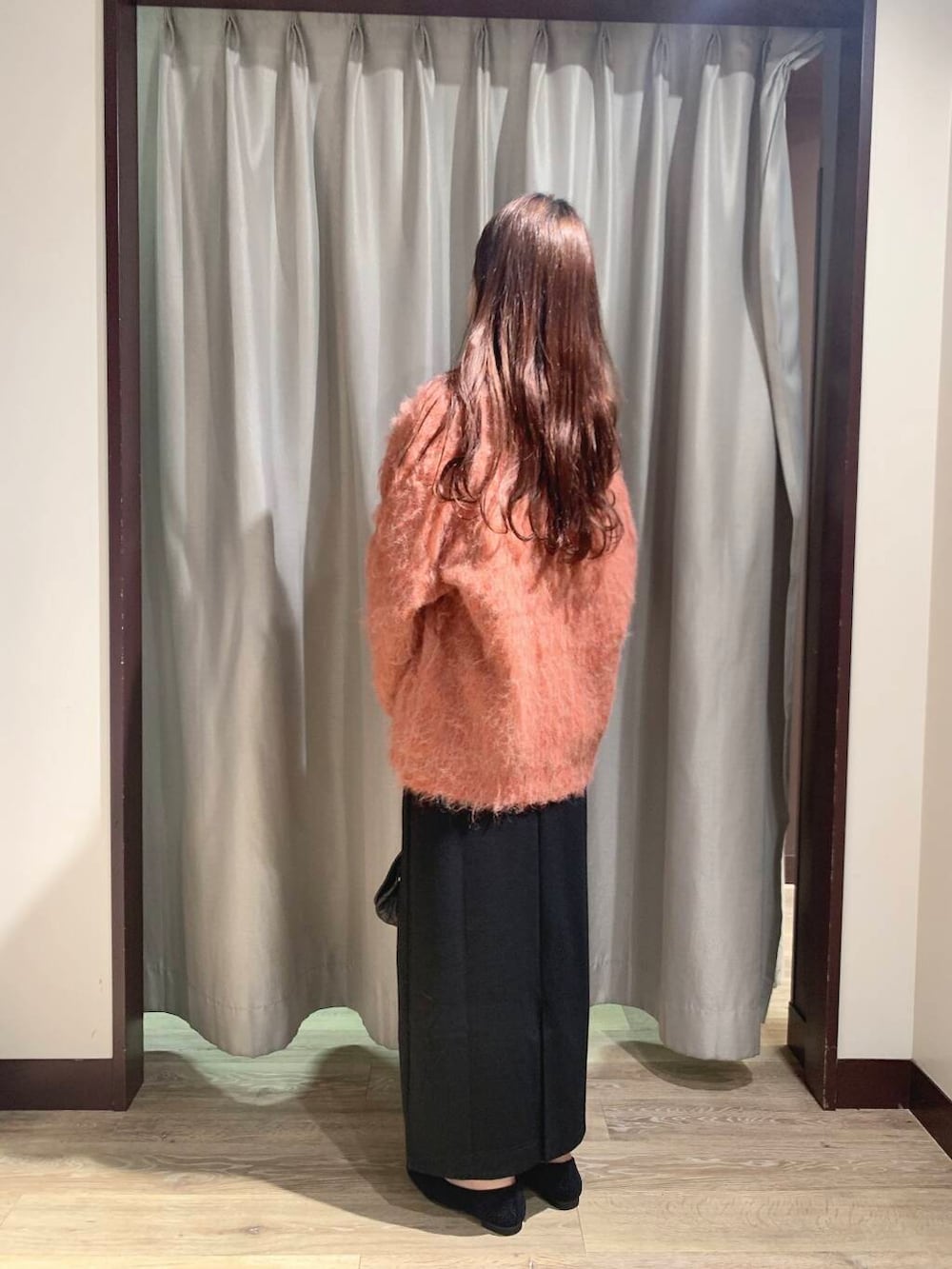 ブラック系のショルダーバッグ、オレンジ系のカーディガン/ボレロ、ブラック系のスカートを着用したレディースの秋コーディネートの2枚目の写真