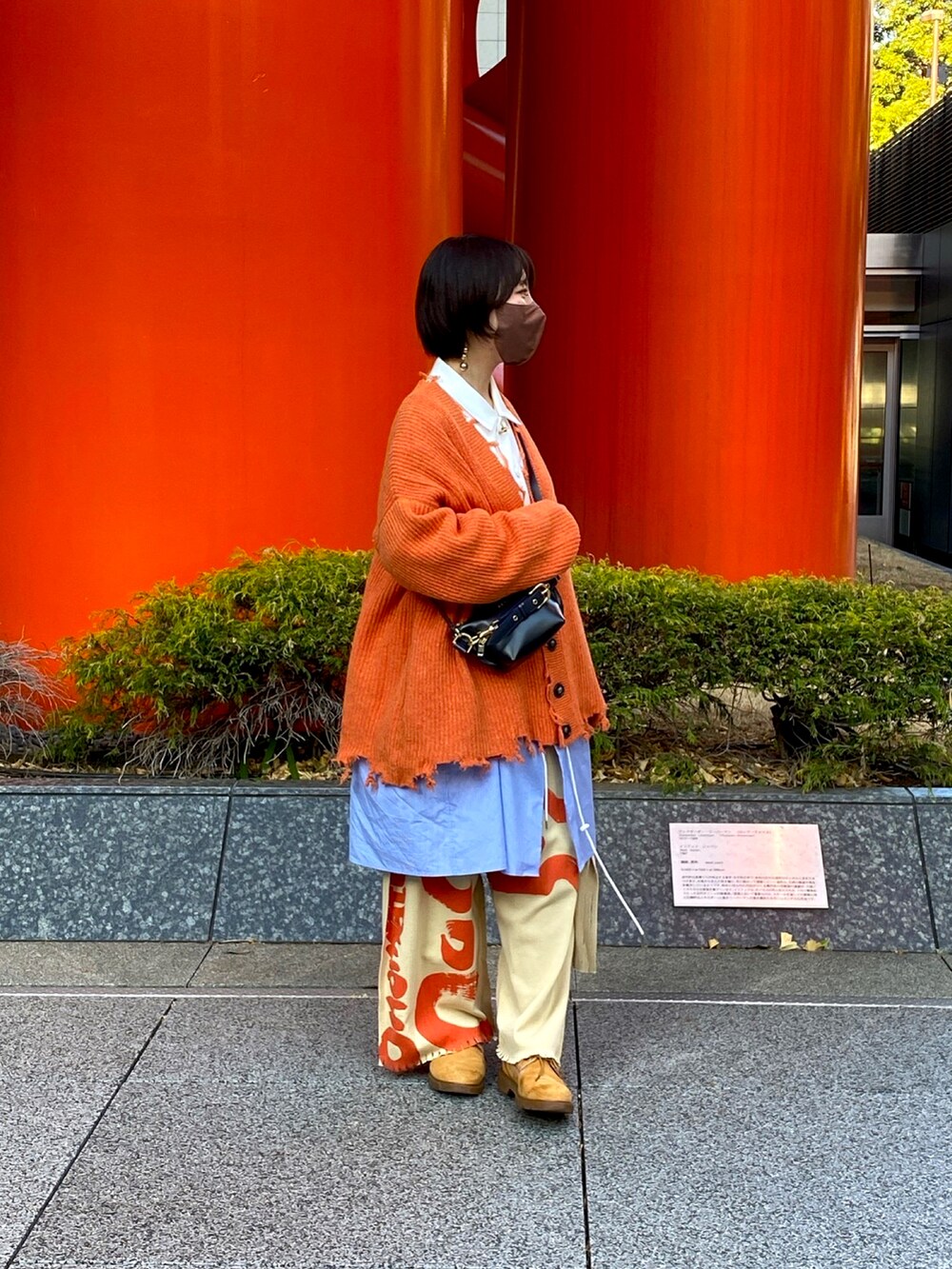 オレンジ系のカーディガン/ボレロ、ブラック系のショルダーバッグ、ホワイト系のシャツ/ブラウスを着用したレディースの冬コーディネートの2枚目の写真