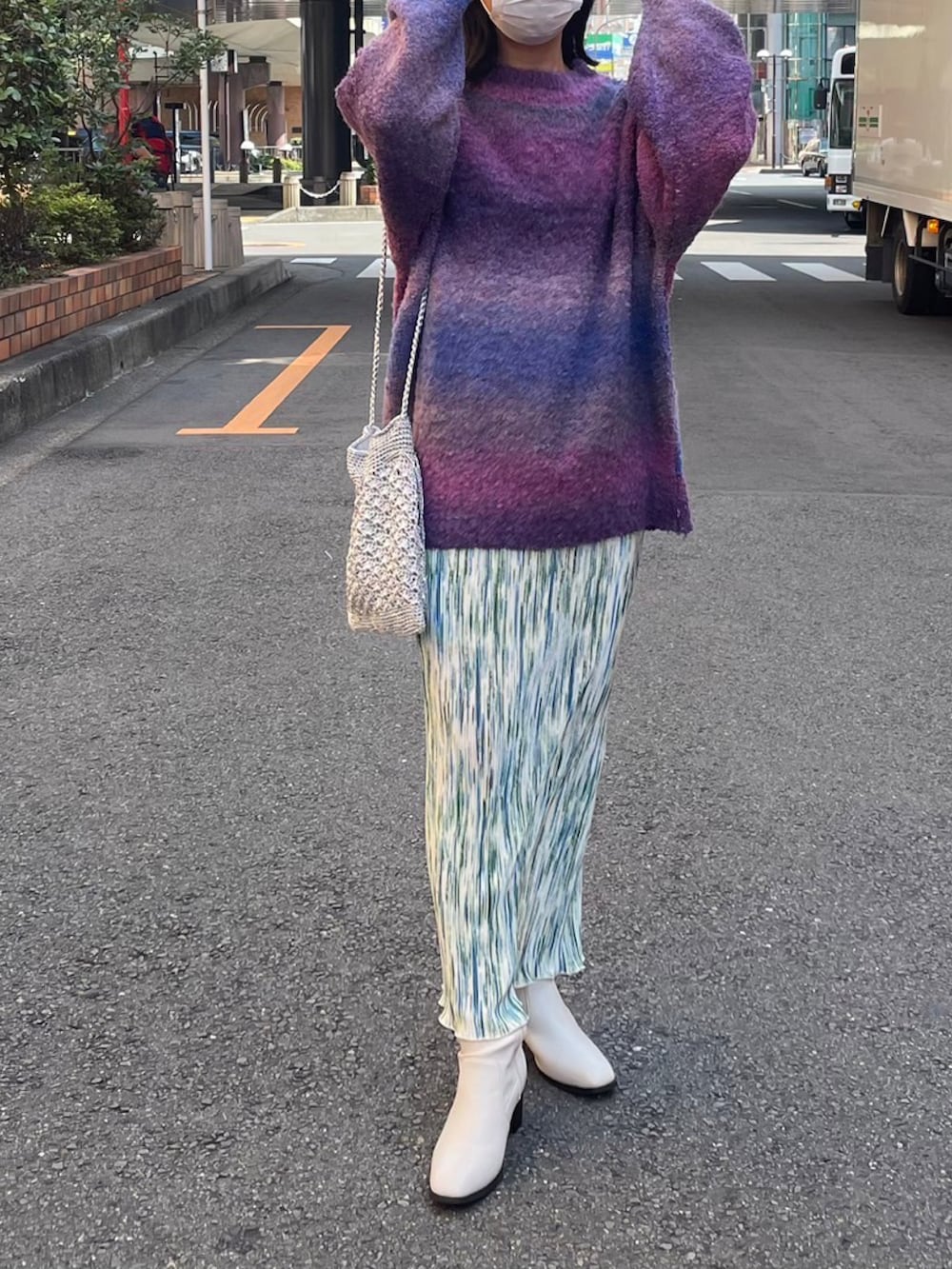 パープル系のニット/セーター、グリーン系のスカート、シルバー系のショルダーバッグを着用したレディースの秋コーディネートの2枚目の写真