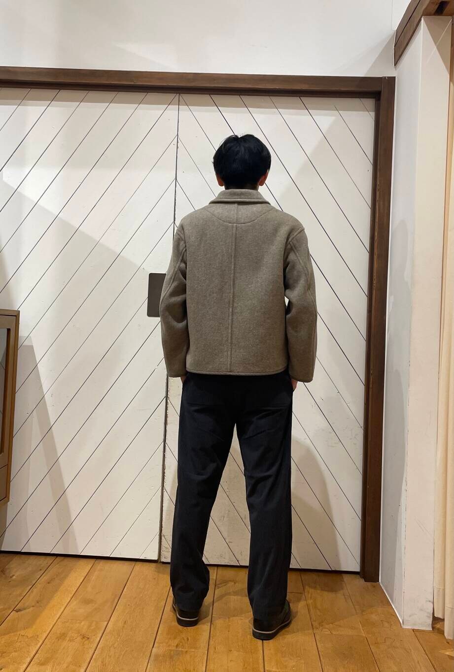オレンジ系のニット/セーター、グレー系のその他パンツ、ベージュ系のカバーオールを着用したメンズの冬コーディネートの3枚目の写真