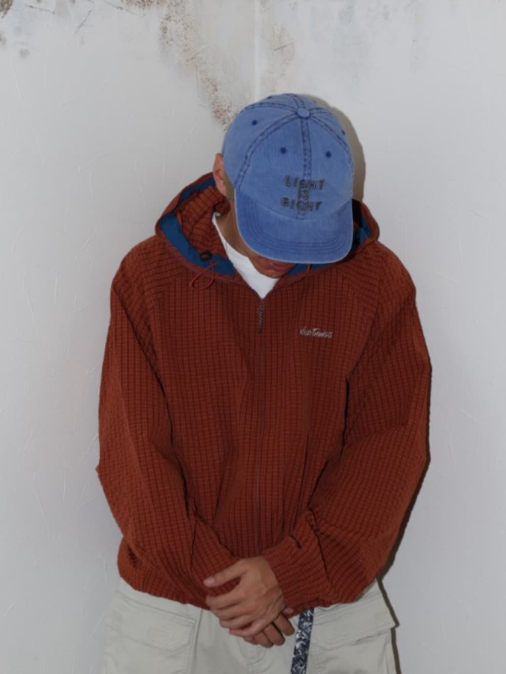 オレンジ系のパーカー、ブルー系のキャップを着用したメンズの夏コーディネートの2枚目の写真