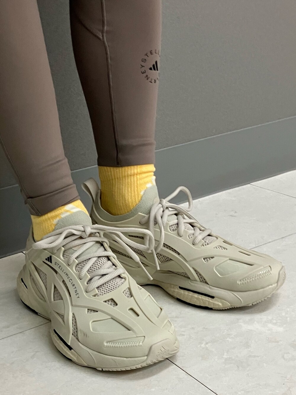 ベージュ系のスニーカー、グレー系のパーカー、ブラウン系のスポーツブラを着用したレディースの春コーディネートの4枚目の写真