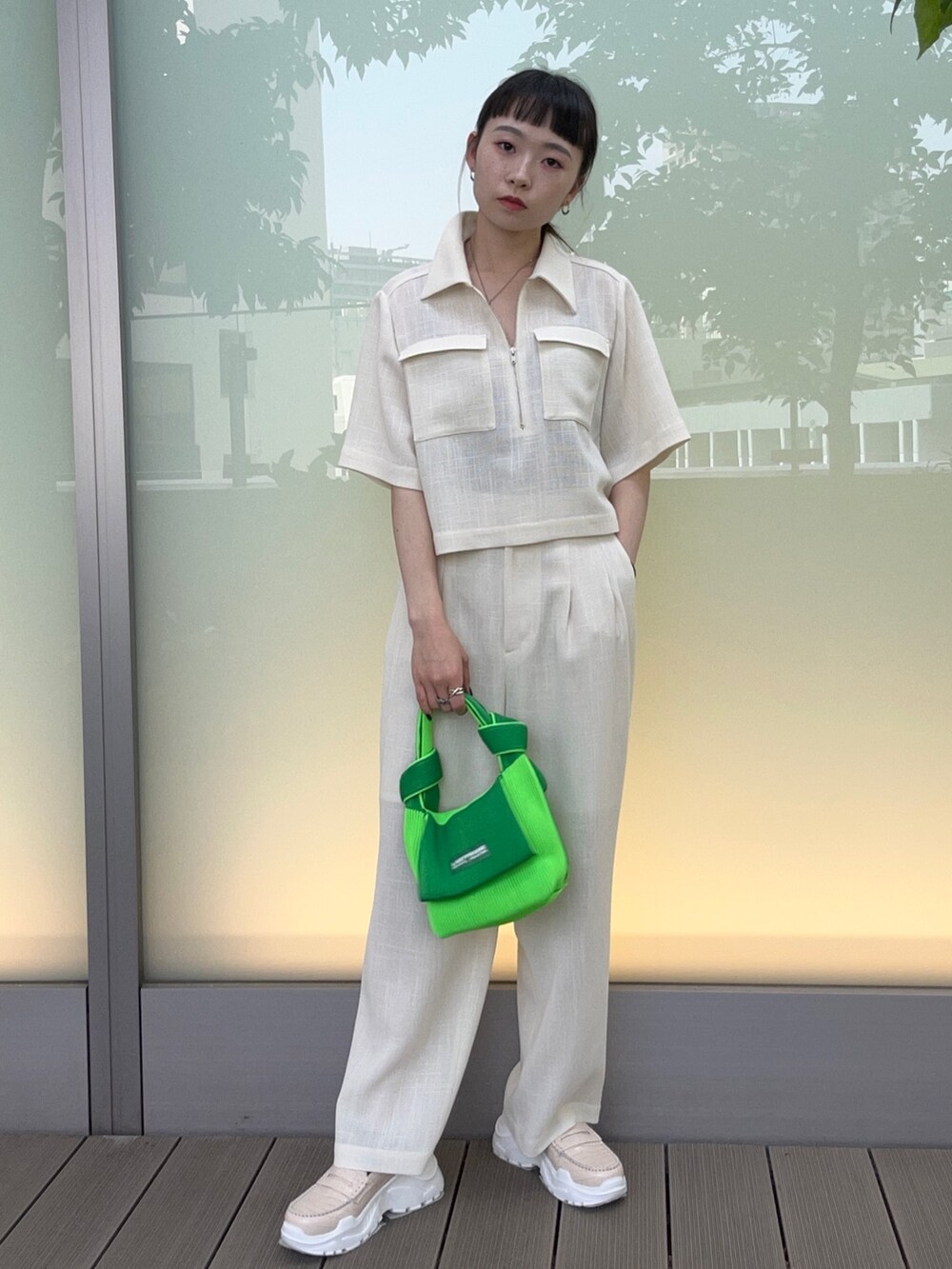 グリーン系のハンドバッグ、ホワイト系のスラックス、ホワイト系のシャツ/ブラウスを着用したレディースの春コーディネートの5枚目の写真