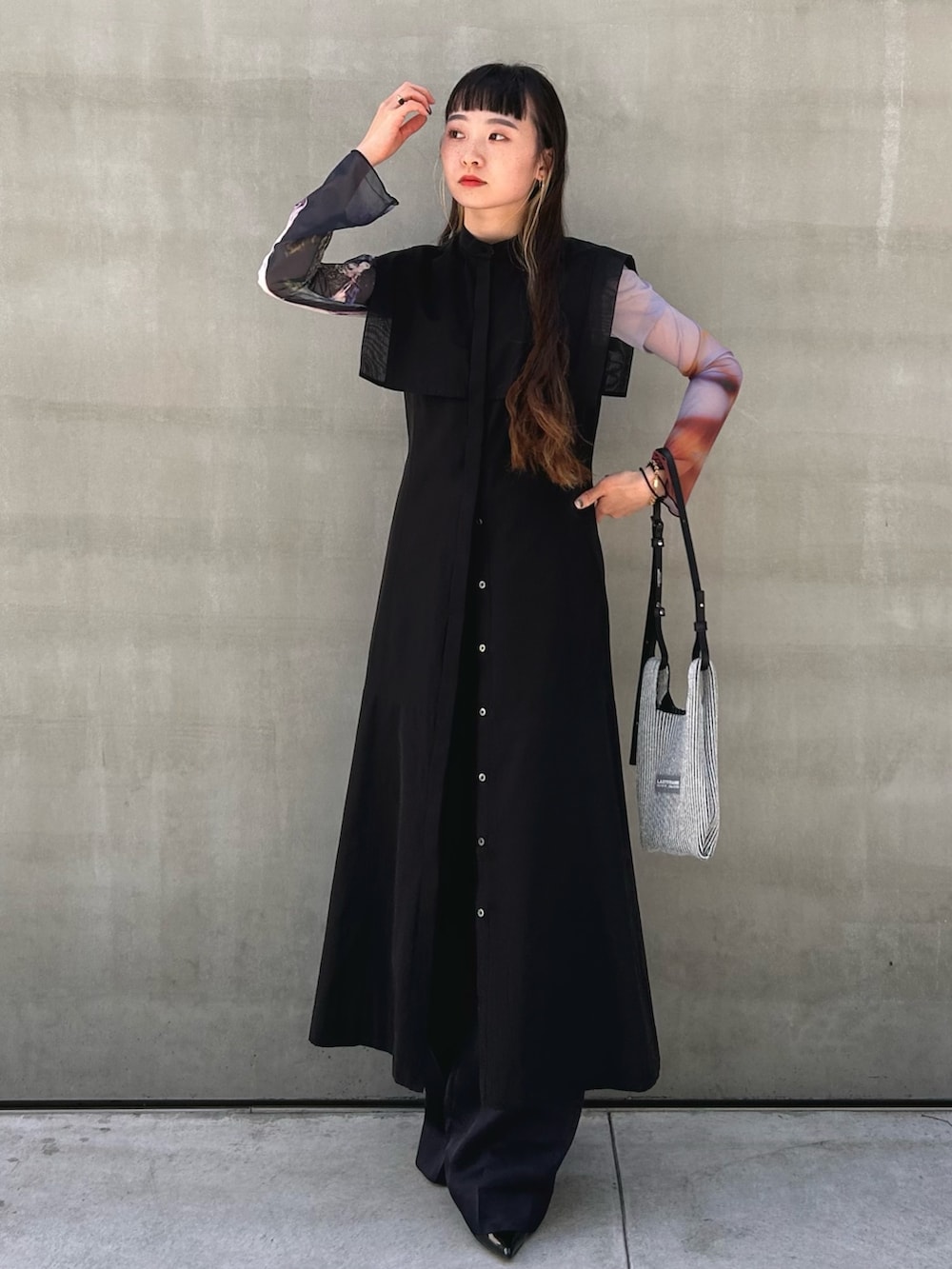 ブラック系のワンピース、シルバー系のショルダーバッグを着用したレディースの春コーディネートの3枚目の写真