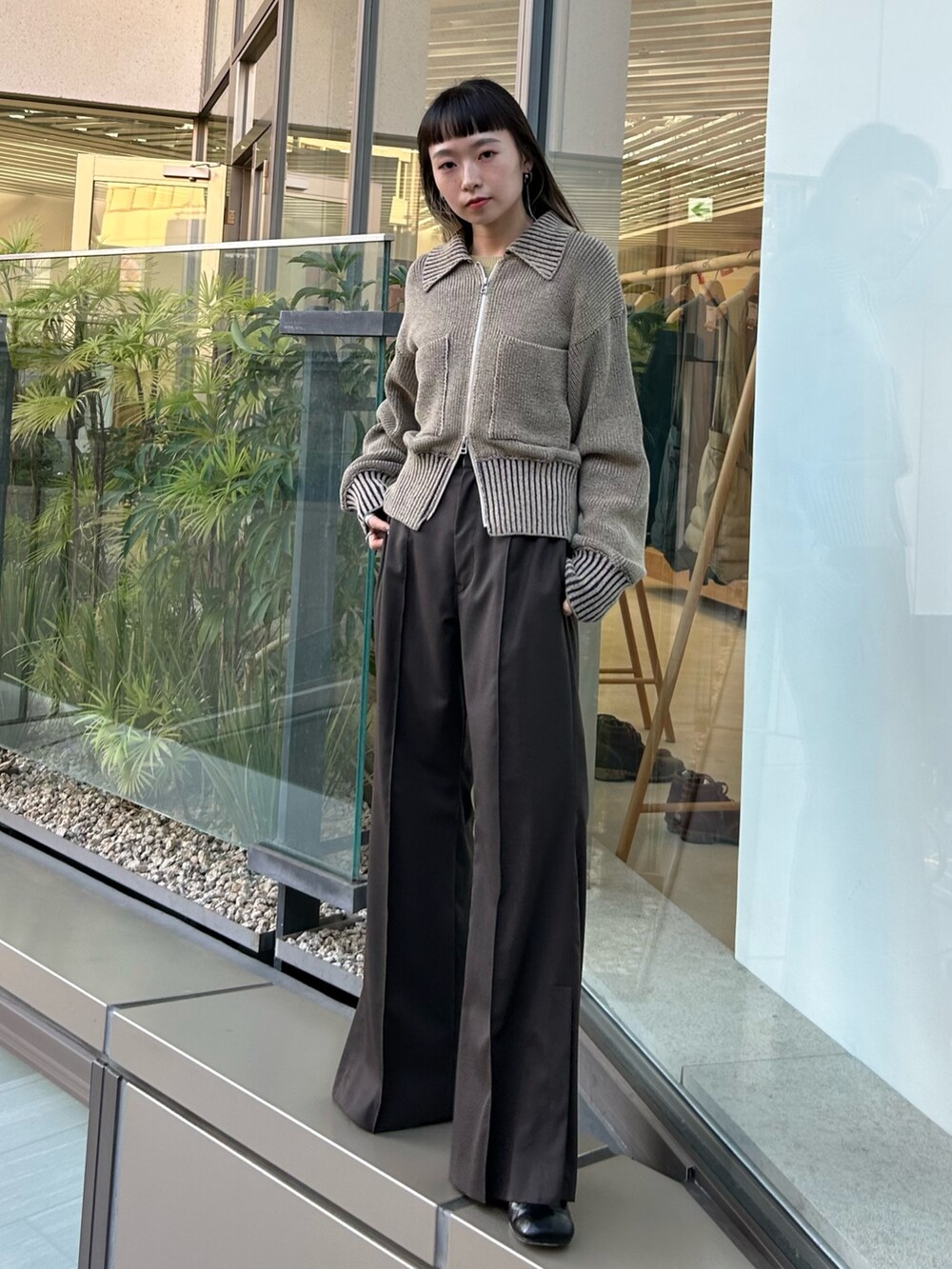 ブラウン系のスラックス、ブラック系のブーツを着用したレディースの秋コーディネートの2枚目の写真