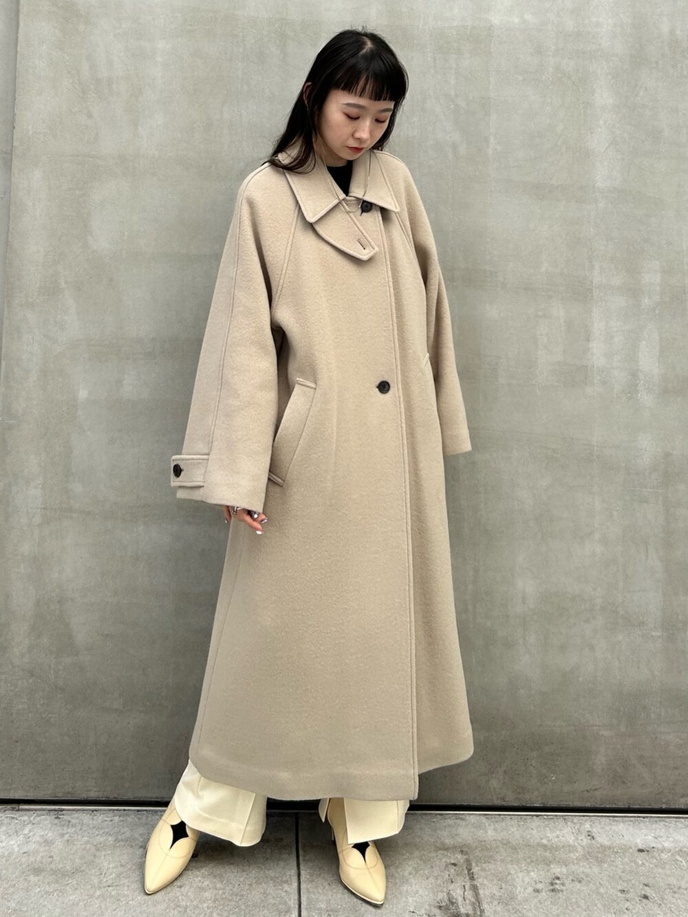 ベージュ系のステンカラーコートを着用したレディースの秋コーディネートの2枚目の写真
