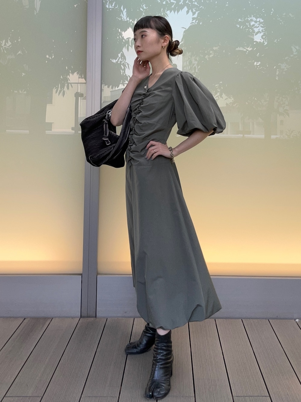 ブラック系のハンドバッグ、グリーン系のワンピースを着用したレディースの春コーディネートの3枚目の写真