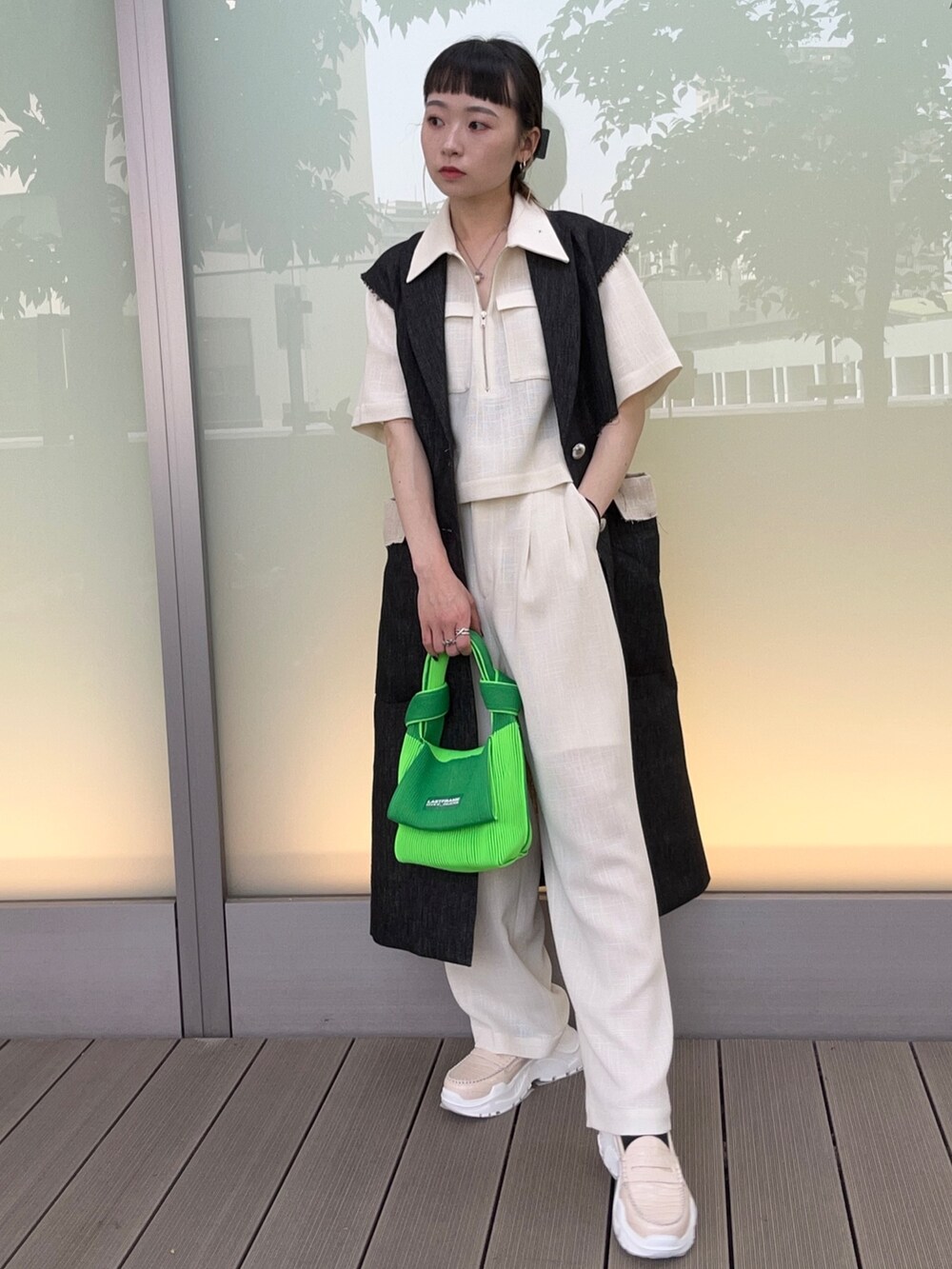グリーン系のハンドバッグ、ホワイト系のスラックス、ホワイト系のシャツ/ブラウスを着用したレディースの春コーディネートの2枚目の写真