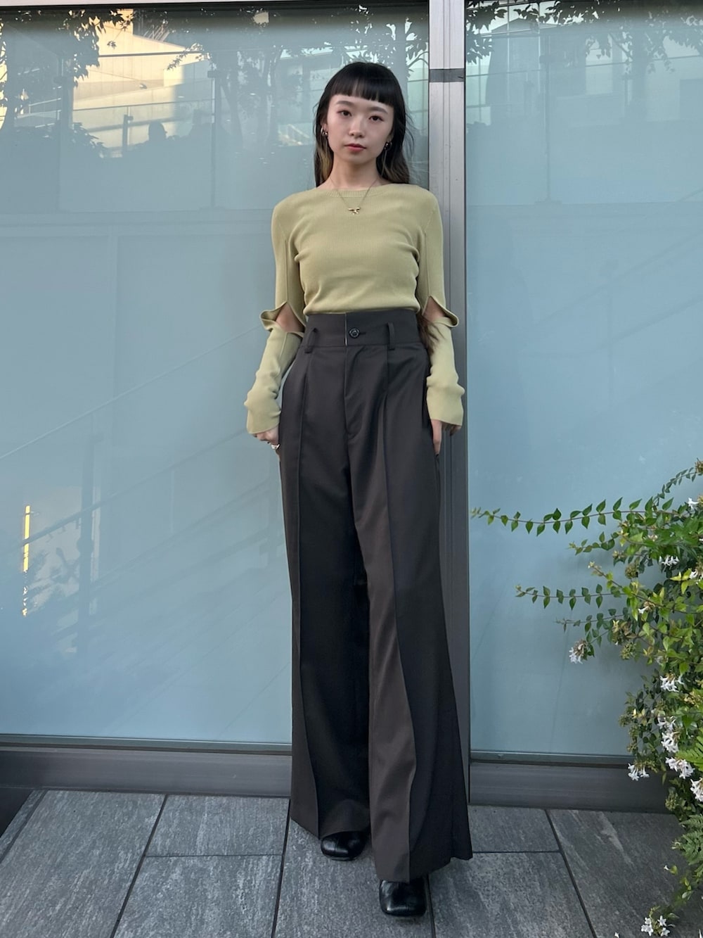 ブラウン系のスラックス、ベージュ系のニット/セーター、ブラック系のブーツを着用したレディースの秋コーディネートの3枚目の写真