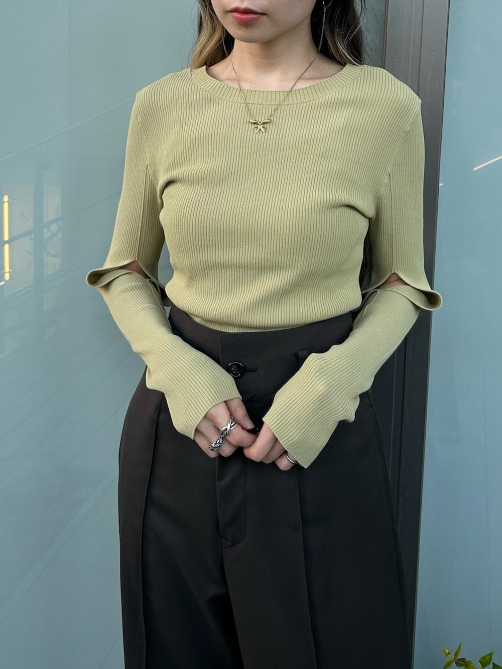 ブラウン系のスラックス、ベージュ系のニット/セーター、ブラック系のブーツを着用したレディースの秋コーディネートの4枚目の写真