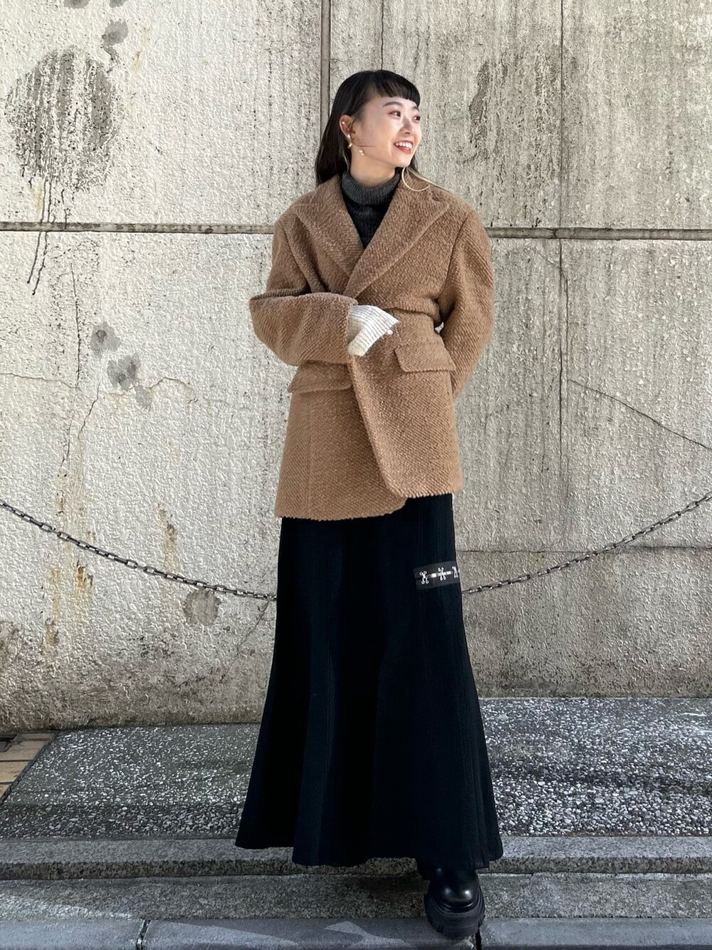 ブラック系のスカート、イエロー系のその他アウター、グリーン系のニット/セーターを着用したレディースの冬コーディネートの3枚目の写真