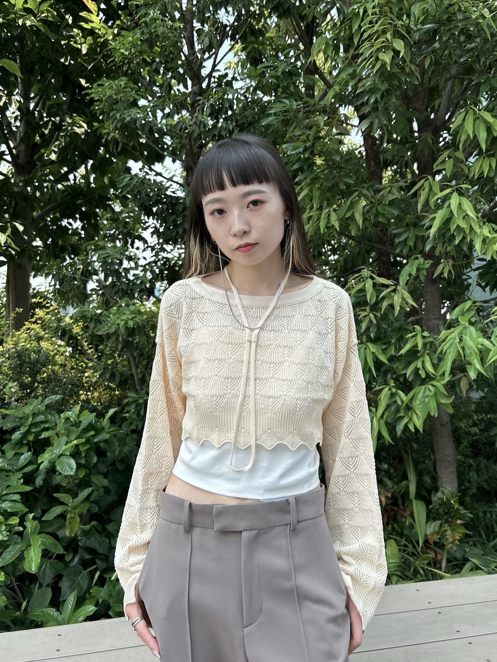 グレー系のスラックス、ホワイト系のニット/セーター、ブラック系のブーツを着用したレディースの夏コーディネートの4枚目の写真