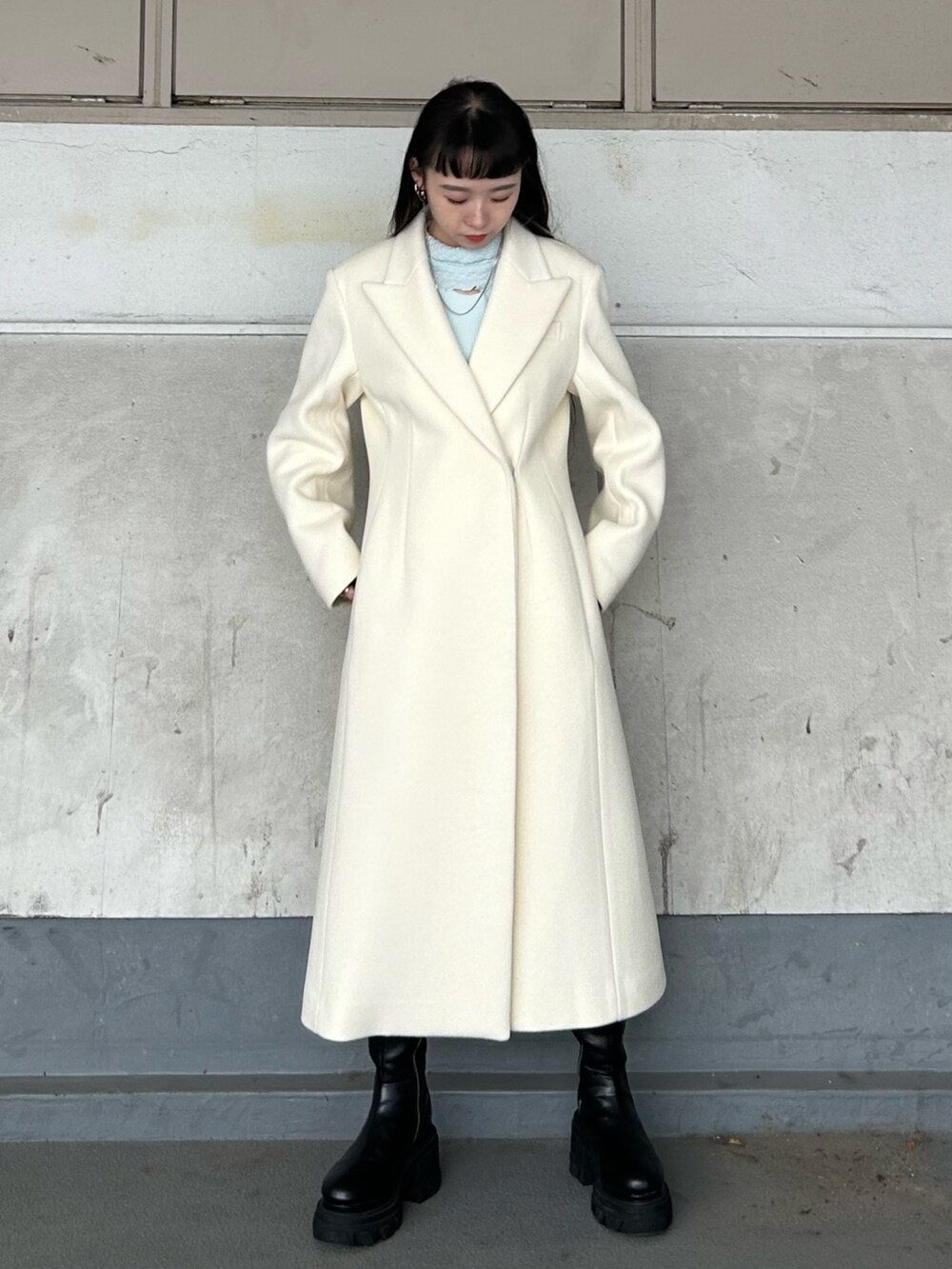 ブラック系のブーツ、ホワイト系のチェスターコート、ブルー系のTシャツ/カットソーを着用したレディースの秋コーディネートの4枚目の写真