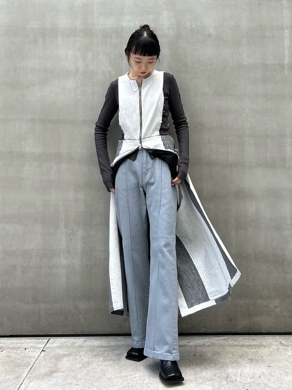 グレー系のTシャツ/カットソー、ブラック系のブーツ、ブルー系のデニムパンツを着用したレディースの秋コーディネートの4枚目の写真