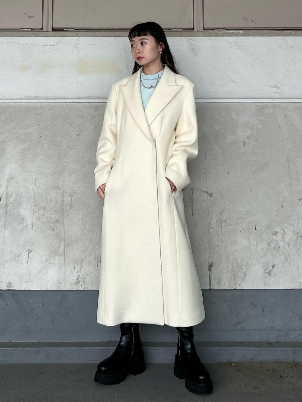 ブラック系のブーツ、ホワイト系のチェスターコート、ブルー系のTシャツ/カットソーを着用したレディースの秋コーディネートの2枚目の写真