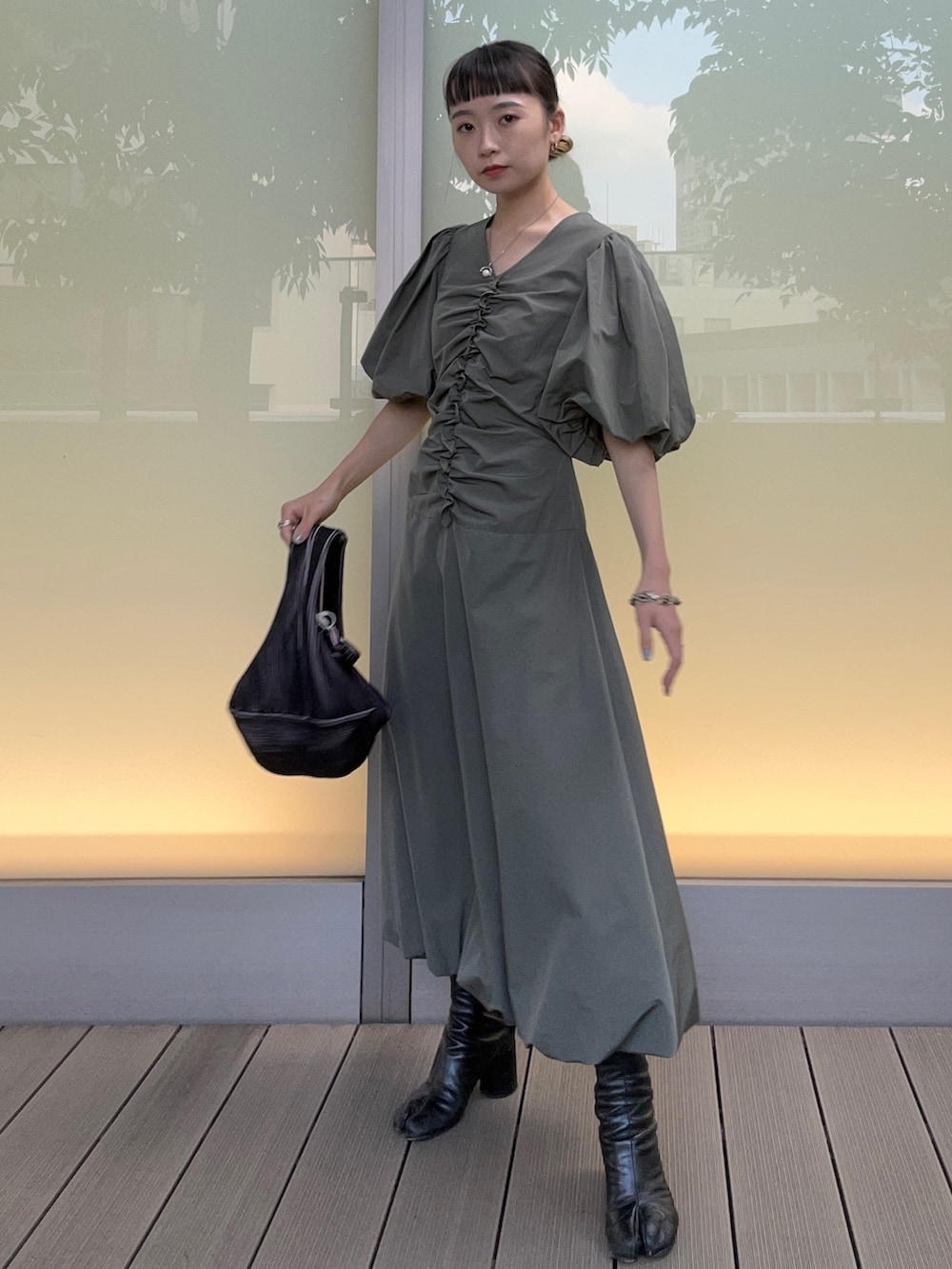 ブラック系のハンドバッグ、グリーン系のワンピースを着用したレディースの春コーディネートの2枚目の写真