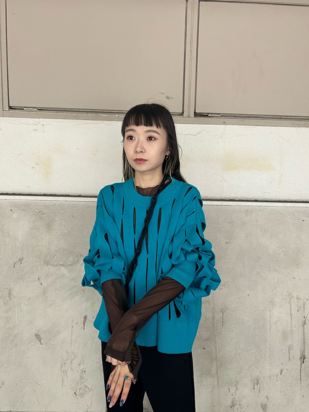 ブラウン系のTシャツ/カットソー、ブルー系のニット/セーター、ブラック系のスマホグッズを着用したレディースの秋コーディネートの3枚目の写真
