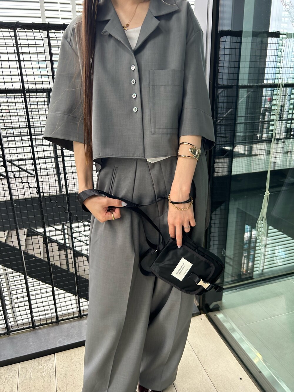グレー系のシャツ/ブラウス、ブラック系のショルダーバッグ、ブラック系のスラックスを着用したレディースの夏コーディネートの5枚目の写真