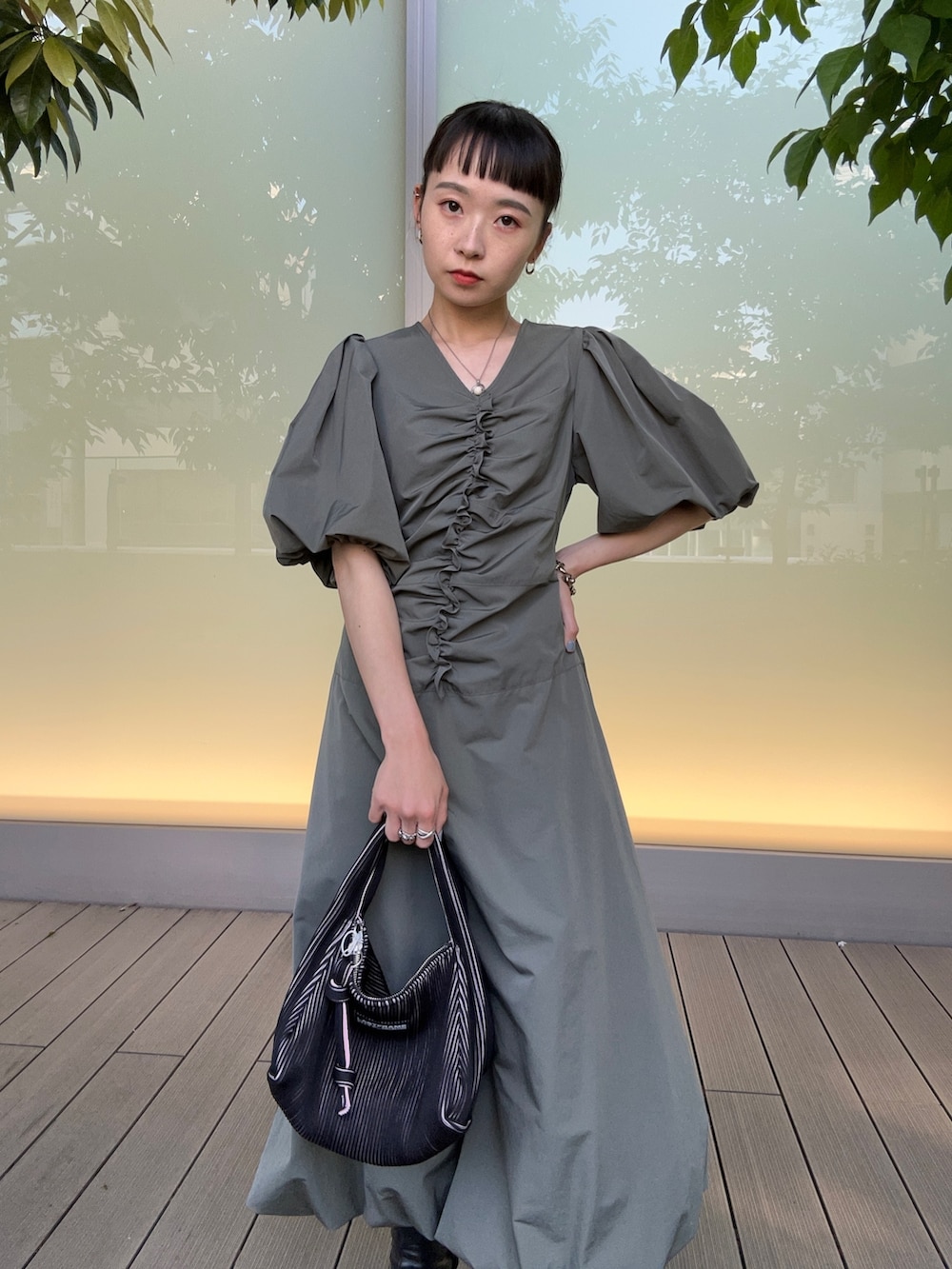 ブラック系のハンドバッグ、グリーン系のワンピースを着用したレディースの春コーディネートの5枚目の写真