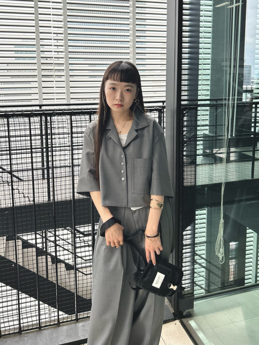グレー系のシャツ/ブラウス、ブラック系のショルダーバッグ、ブラック系のスラックスを着用したレディースの夏コーディネートの4枚目の写真