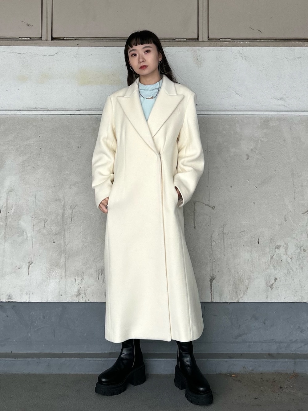 ブラック系のブーツ、ホワイト系のチェスターコート、ブルー系のTシャツ/カットソーを着用したレディースの秋コーディネートの3枚目の写真