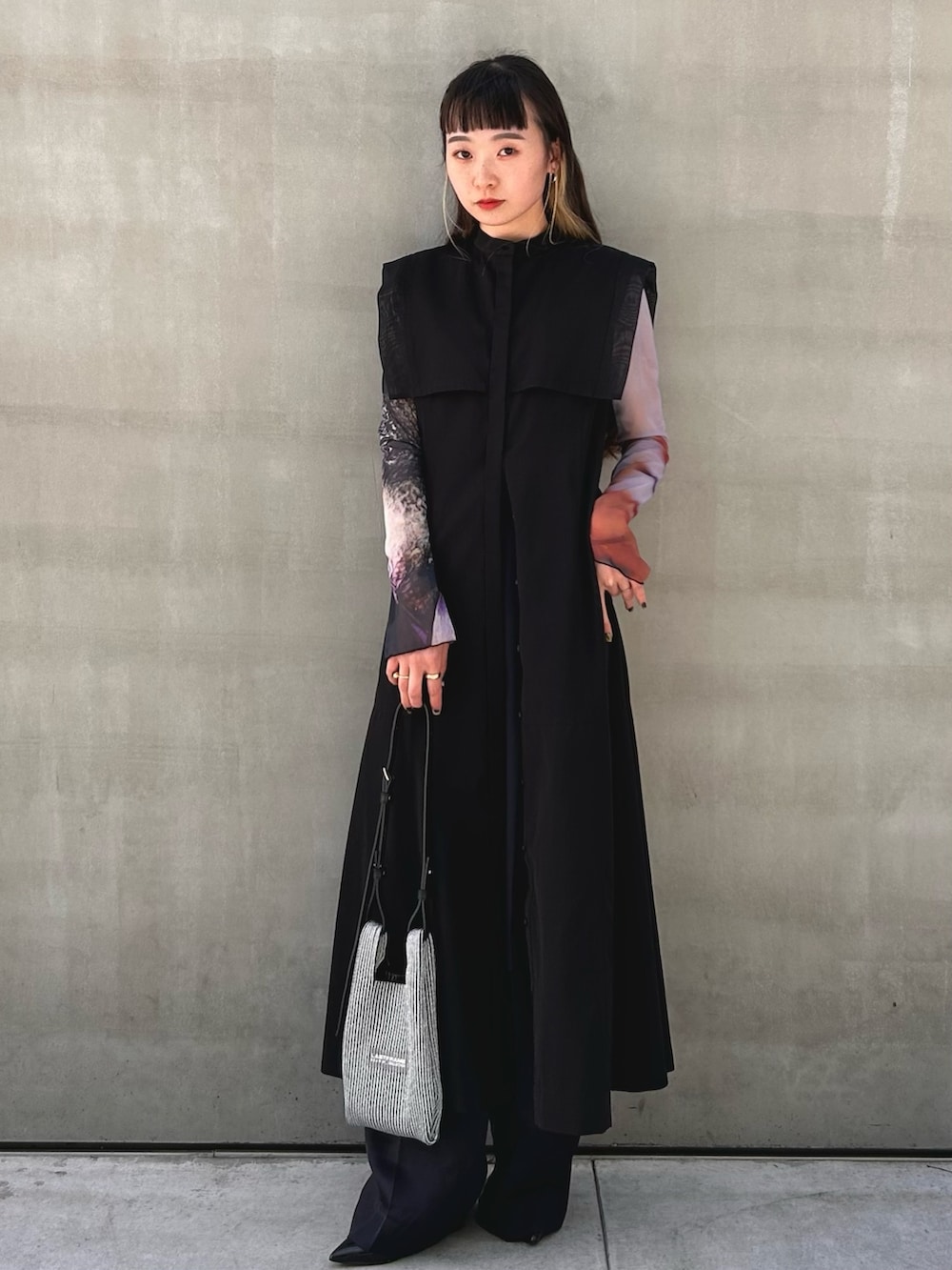 ブラック系のワンピース、シルバー系のショルダーバッグを着用したレディースの春コーディネートの2枚目の写真