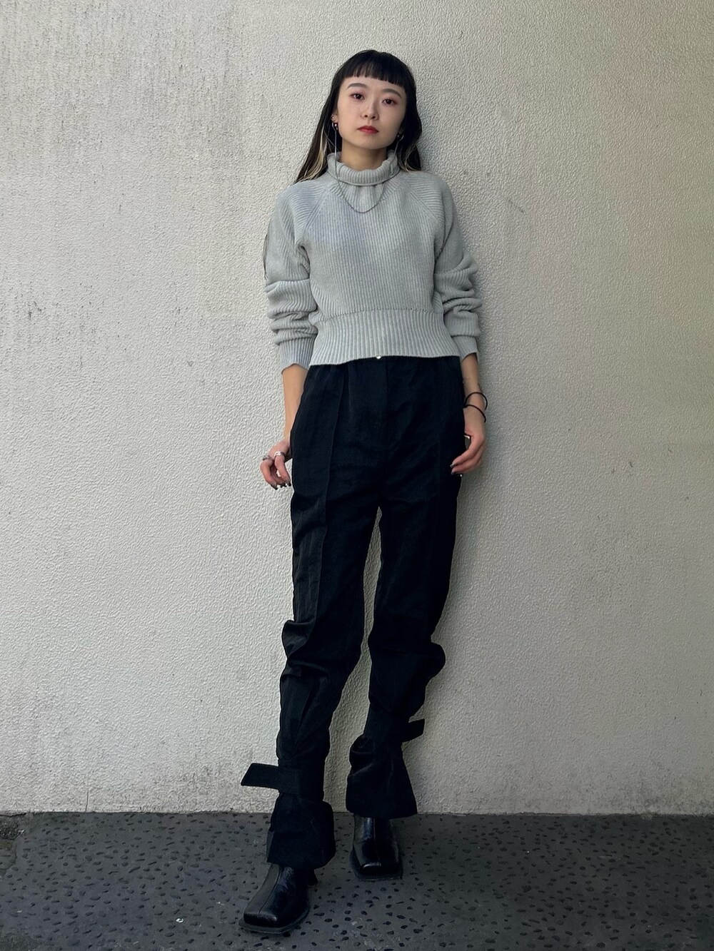 グレー系のニット/セーター、ブラック系のカーゴパンツ、ブラック系のブーツを着用したレディースの秋コーディネートの2枚目の写真