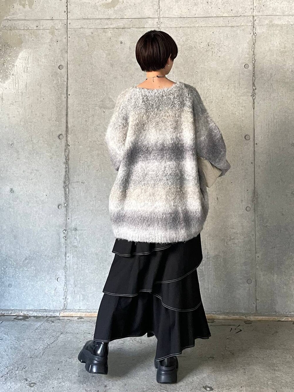 ホワイト系のキャミソール、ブラック系のブーツ、ホワイト系のクラッチバッグを着用したレディースの冬コーディネートの9枚目の写真