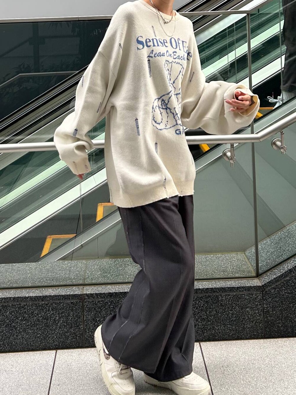 グレー系のスラックス、ホワイト系のニット/セーターを着用したレディースの冬コーディネートの7枚目の写真