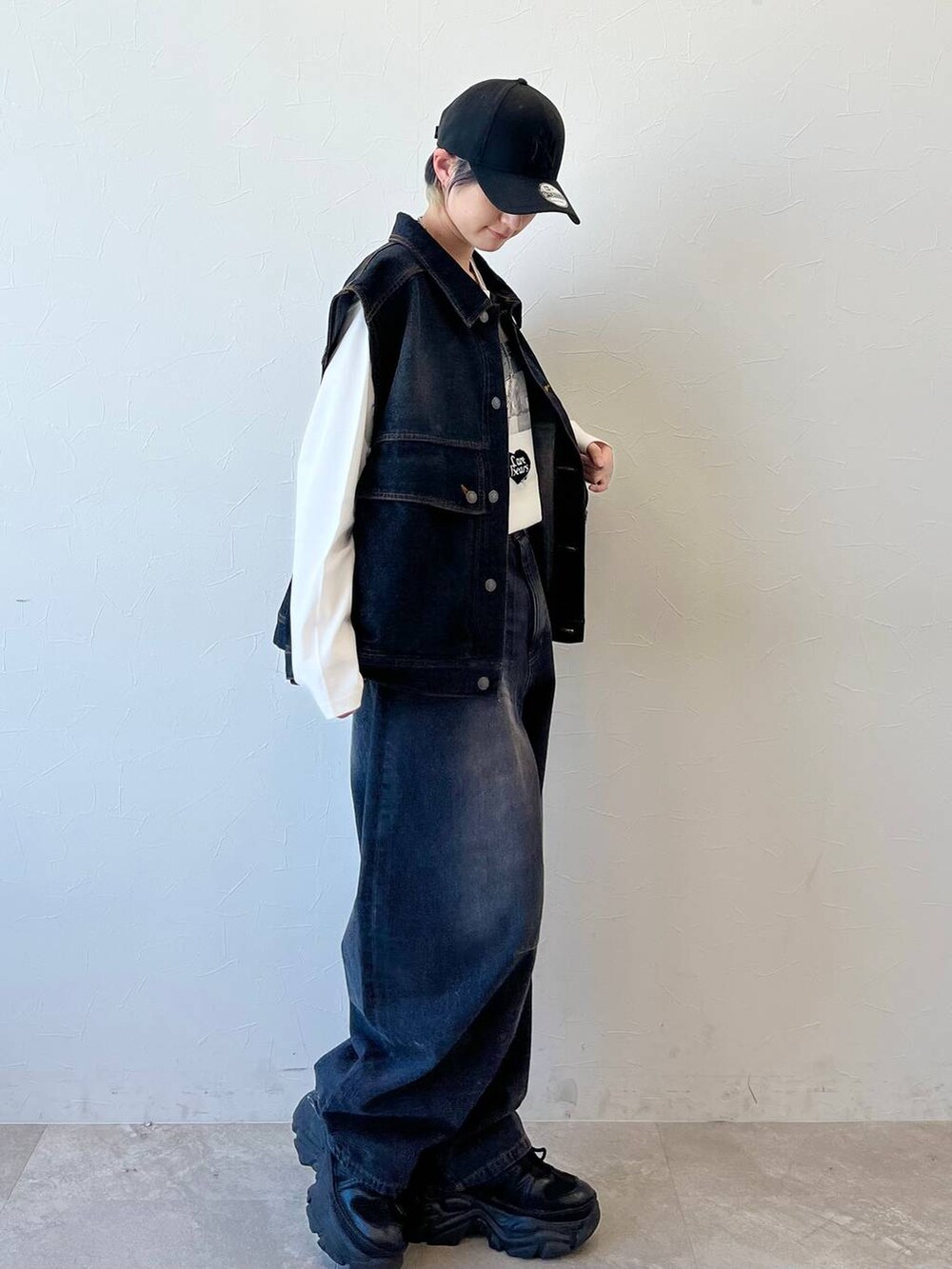 ブラック系のスニーカー、ブラック系のデニムパンツ、ブラウン系のボストンバッグを着用したレディースの春コーディネートの4枚目の写真