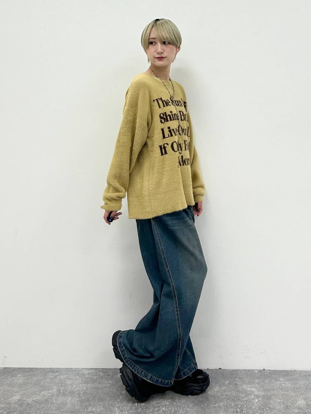 ブラック系のスニーカー、ブルー系のデニムパンツ、イエロー系のニット/セーターを着用したレディースの春コーディネートの6枚目の写真