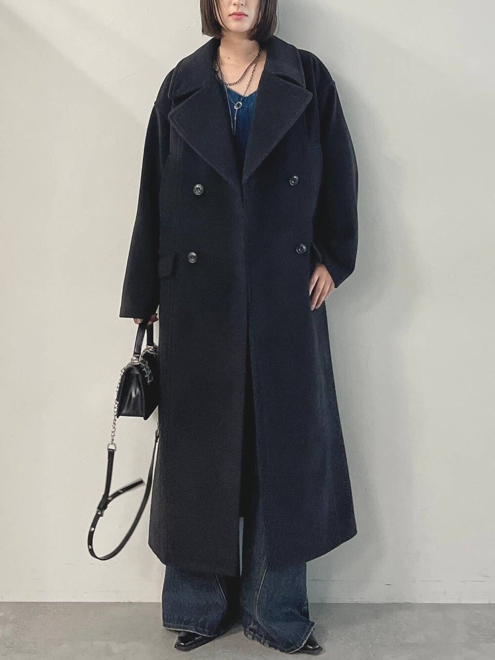 ブルー系のデニムパンツ、ブラック系のパンプス、ブラック系のチェスターコートを着用したレディースの秋コーディネートの4枚目の写真