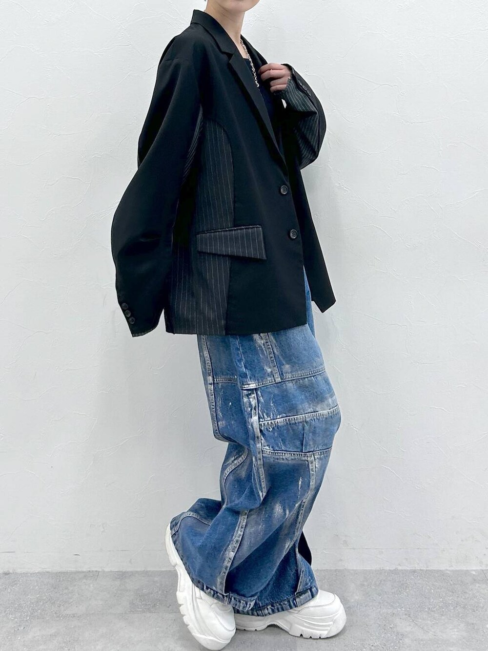 ブラック系のテーラードジャケット、ブルー系のデニムパンツ、シルバー系のネックレスを着用したレディースの春コーディネートの4枚目の写真