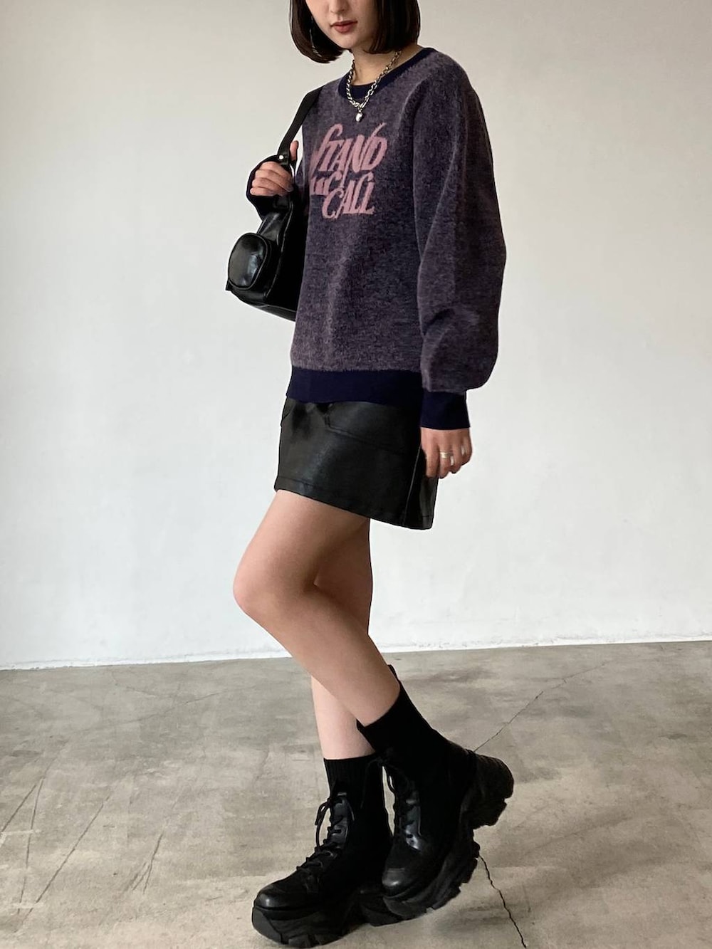 ブラック系のブーツ、ブラック系のスカート、ブラック系のショルダーバッグを着用したレディースの冬コーディネートの4枚目の写真