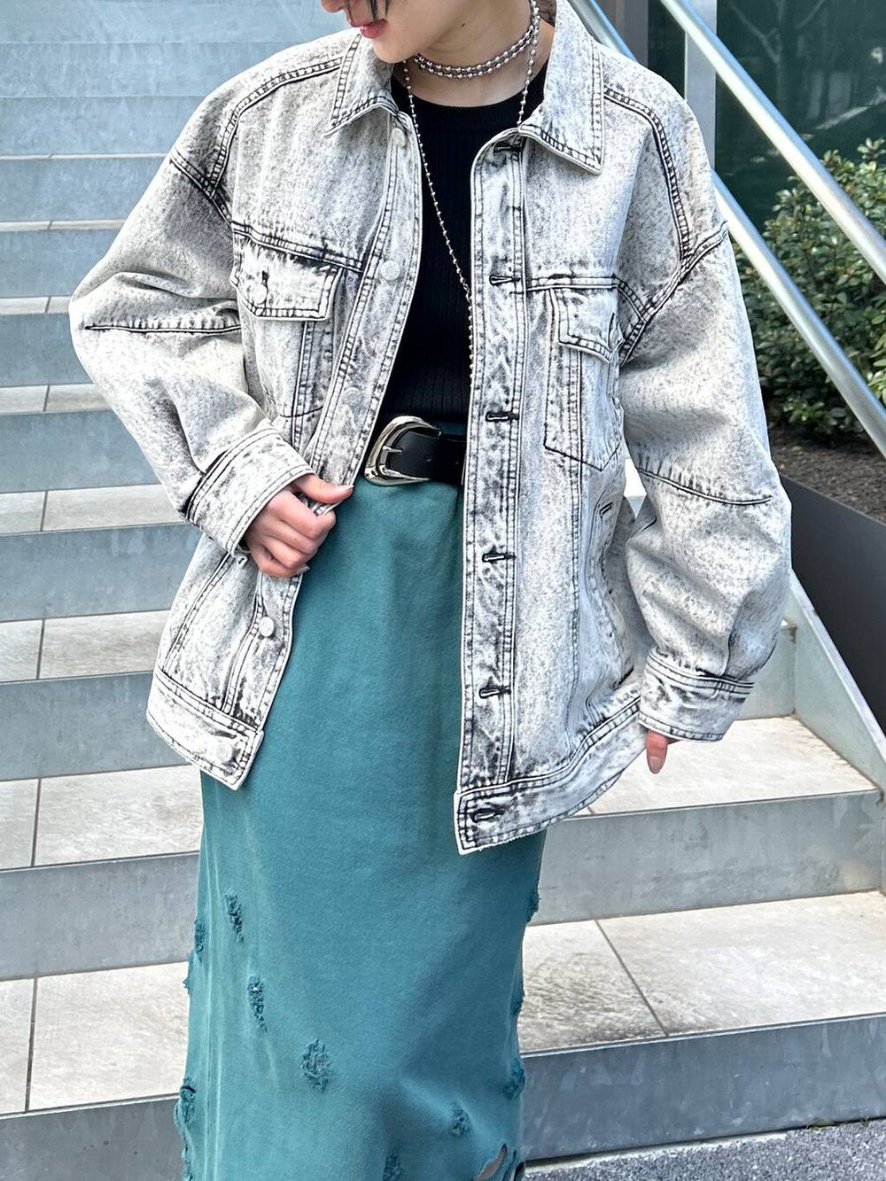 グレー系のデニムジャケット、グリーン系のスカート、ブラック系のキャップを着用したレディースの春コーディネートの4枚目の写真
