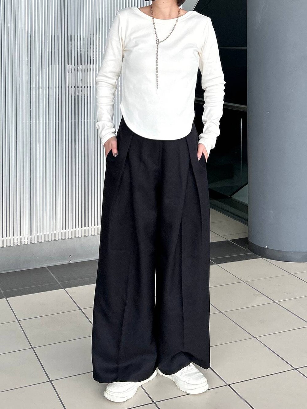 ホワイト系のTシャツ/カットソー、ブラック系のスラックス、シルバー系のネックレスを着用したレディースの春コーディネートの3枚目の写真