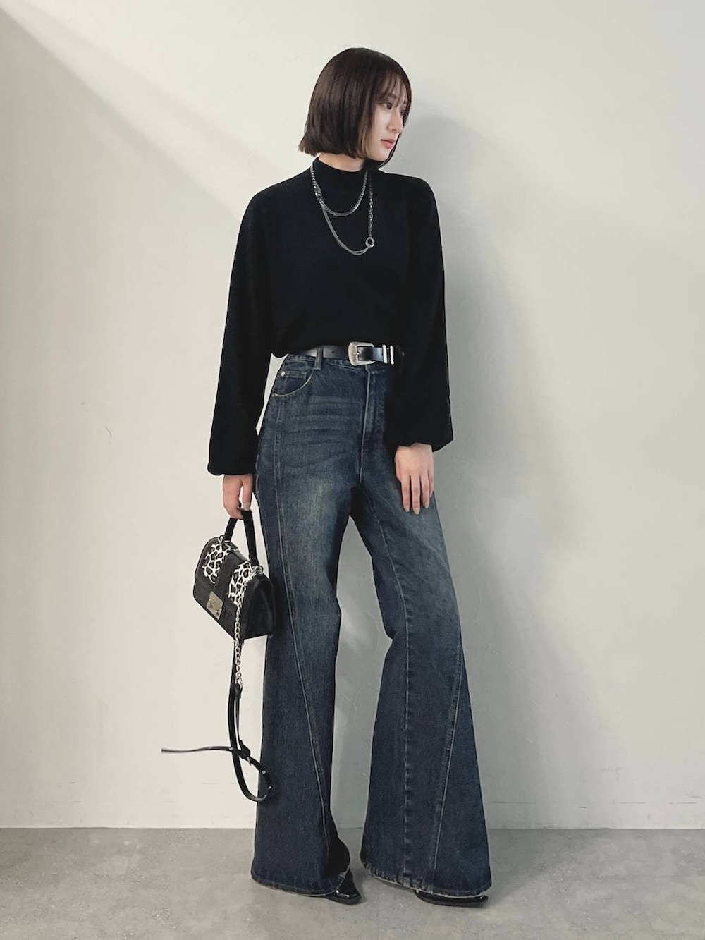 ブルー系のデニムパンツ、ブラック系のパンプス、その他のハンドバッグを着用したレディースの秋コーディネートの2枚目の写真