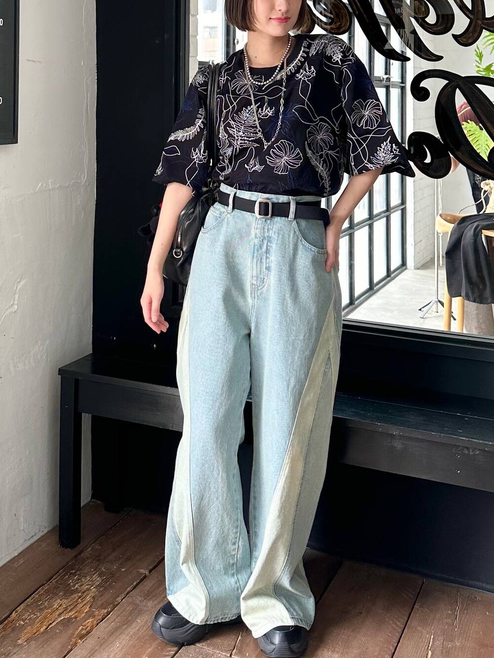 ブラック系のボストンバッグ、ブラック系のTシャツ/カットソー、ブルー系のデニムパンツを着用したレディースの春コーディネートの3枚目の写真