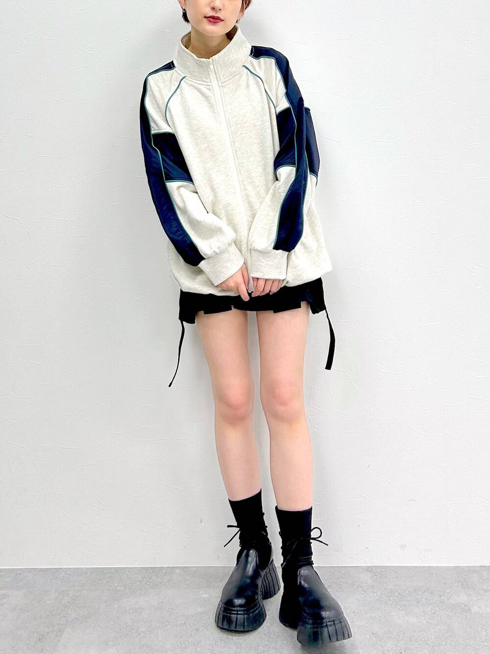 ブラック系のブーツ、ブラック系のスカート、ベージュ系のスウェットを着用したレディースの冬コーディネートの2枚目の写真