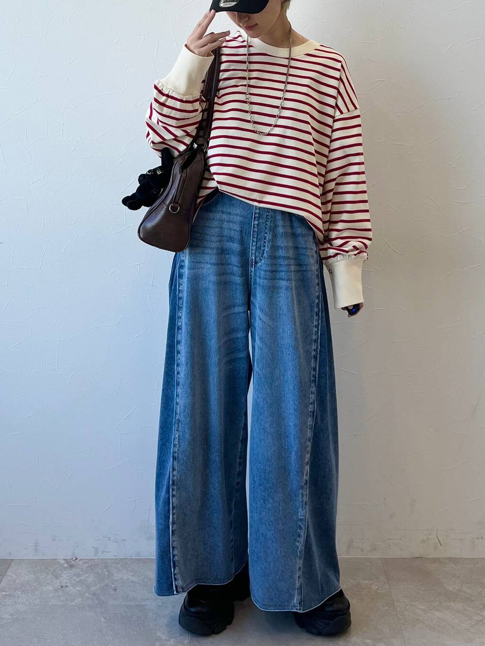 ブラック系のスニーカー、ブラウン系のボストンバッグ、ブルー系のデニムパンツを着用したレディースの春コーディネートの3枚目の写真